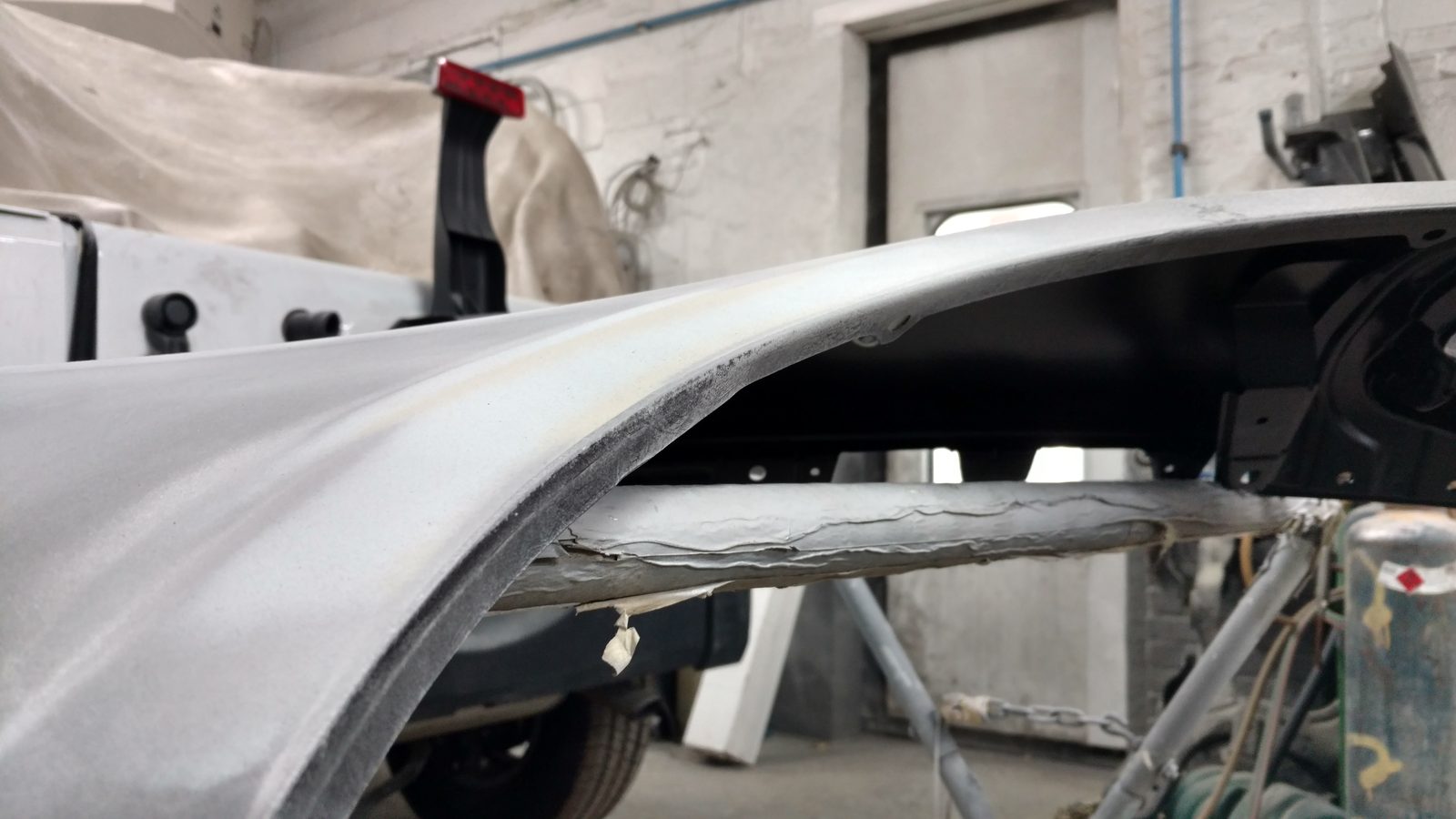 Bare-metal body panel repair in progress inside the shop