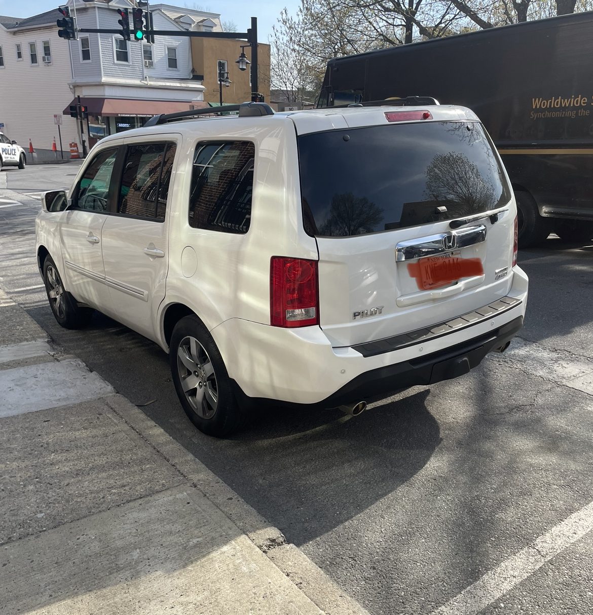 White Honda Pilot at a street intersection with a traffic signal overhead