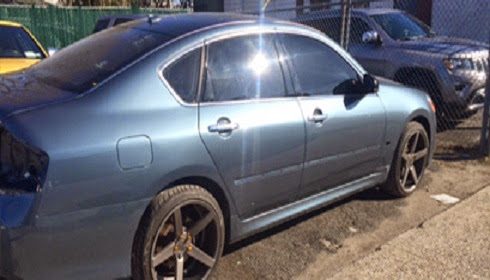 Silver sedan parked along a street beside a fence