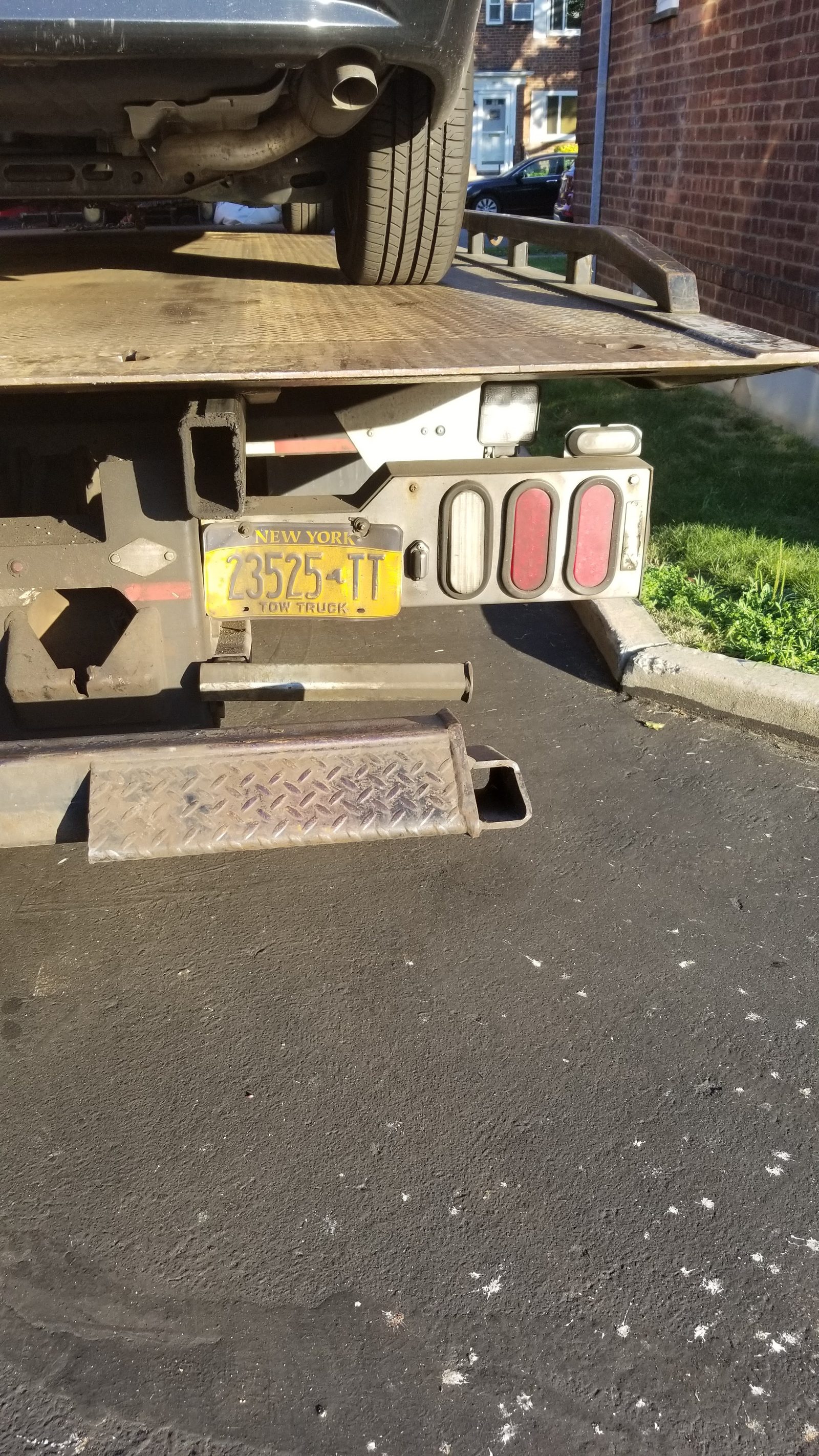 A flatbed carrier with a vehicle on the deck, showing the rear of the truck